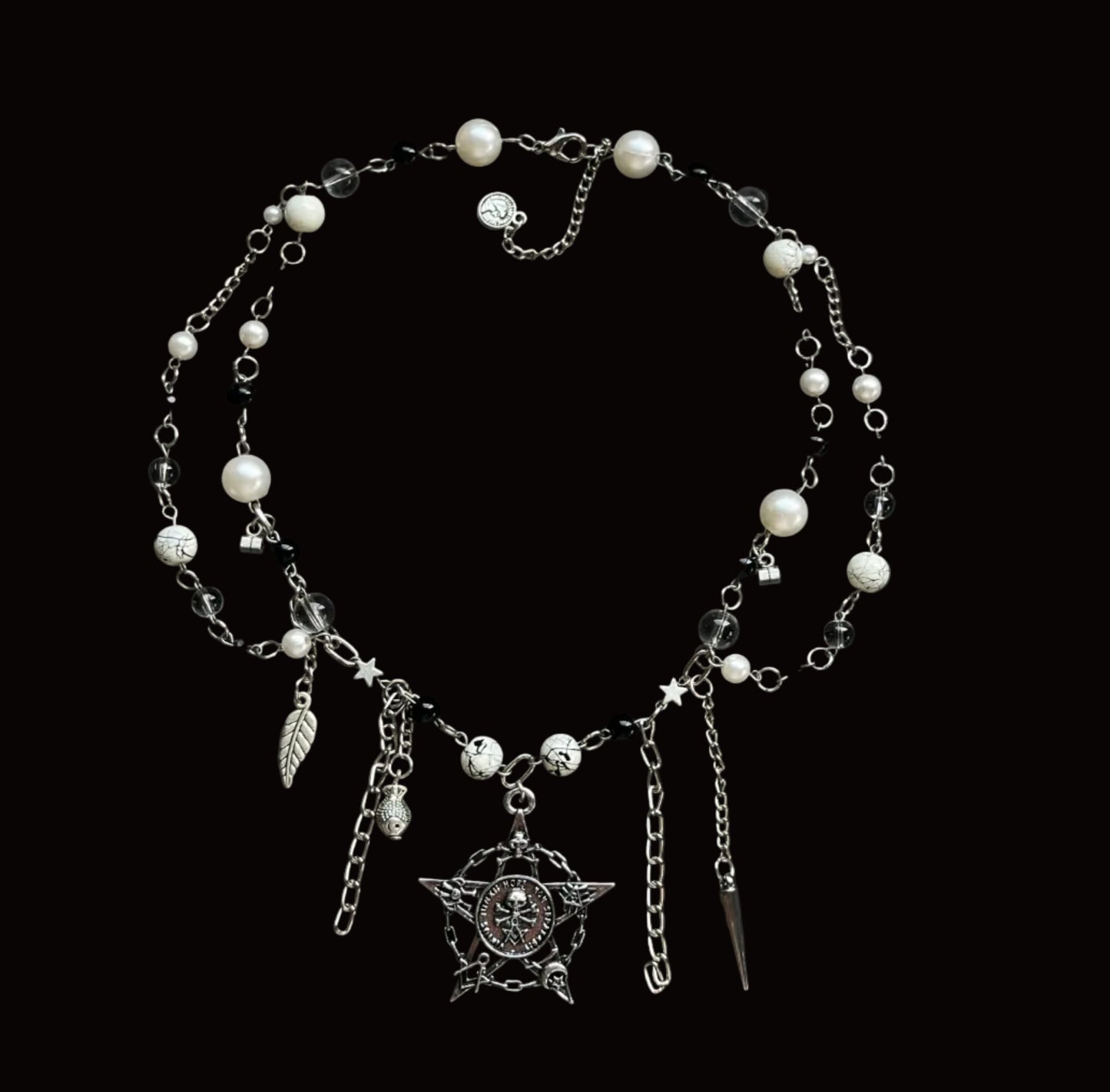 A gothic-style silver chain belt decorated with white faux pearls, a silver crescent moon pendant, a silver leaf charm, and a silver star charm, displayed on a black fabric background.
