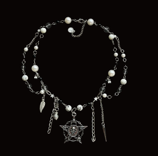 A gothic-style silver chain belt decorated with white faux pearls, a silver crescent moon pendant, a silver leaf charm, and a silver star charm, displayed on a black fabric background.